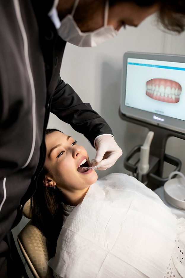 A young woman in the orthodontist chair being fitter with a set of clear aligners for her invisible braces treatment in New York City